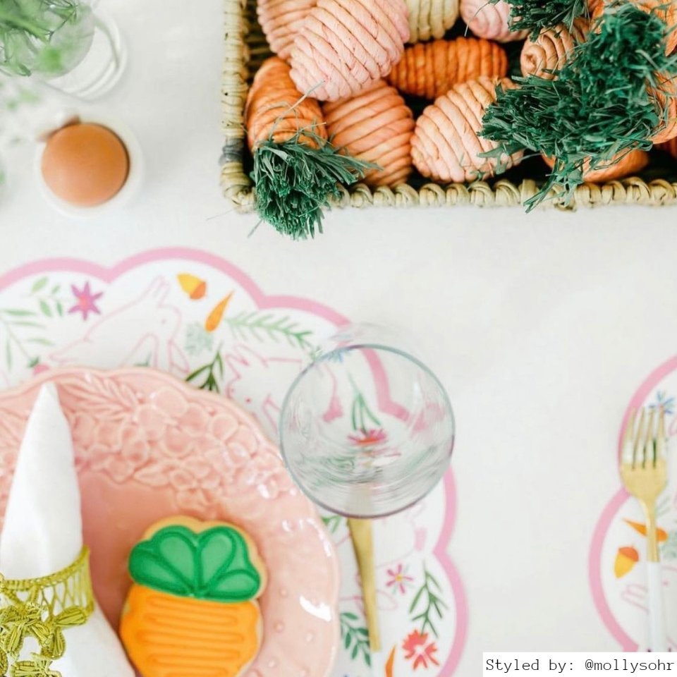 Easter table setting with round bunny paper placemat and other pink and orange Easter table decor